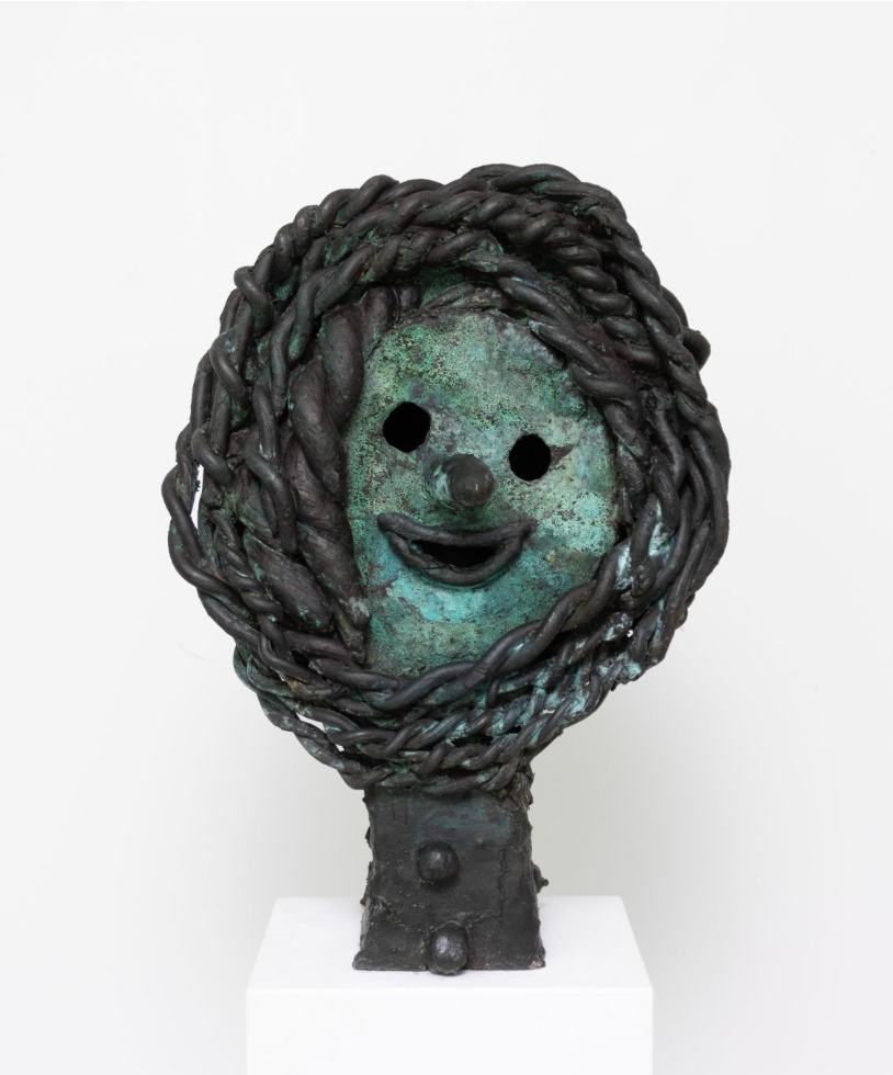 Bronze sculpture of a smiling face surrounded by braided bronze forms with a green patina.