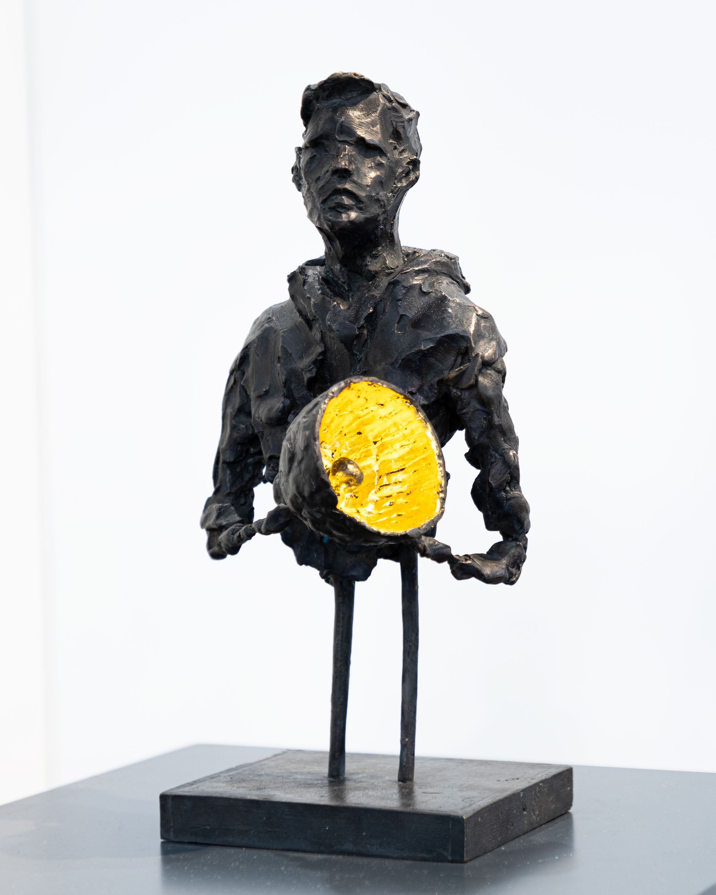 Bronzeskulptur af Jacob Rantzau med en stående figur, der holder et gyldent lys foran kroppen, 2024