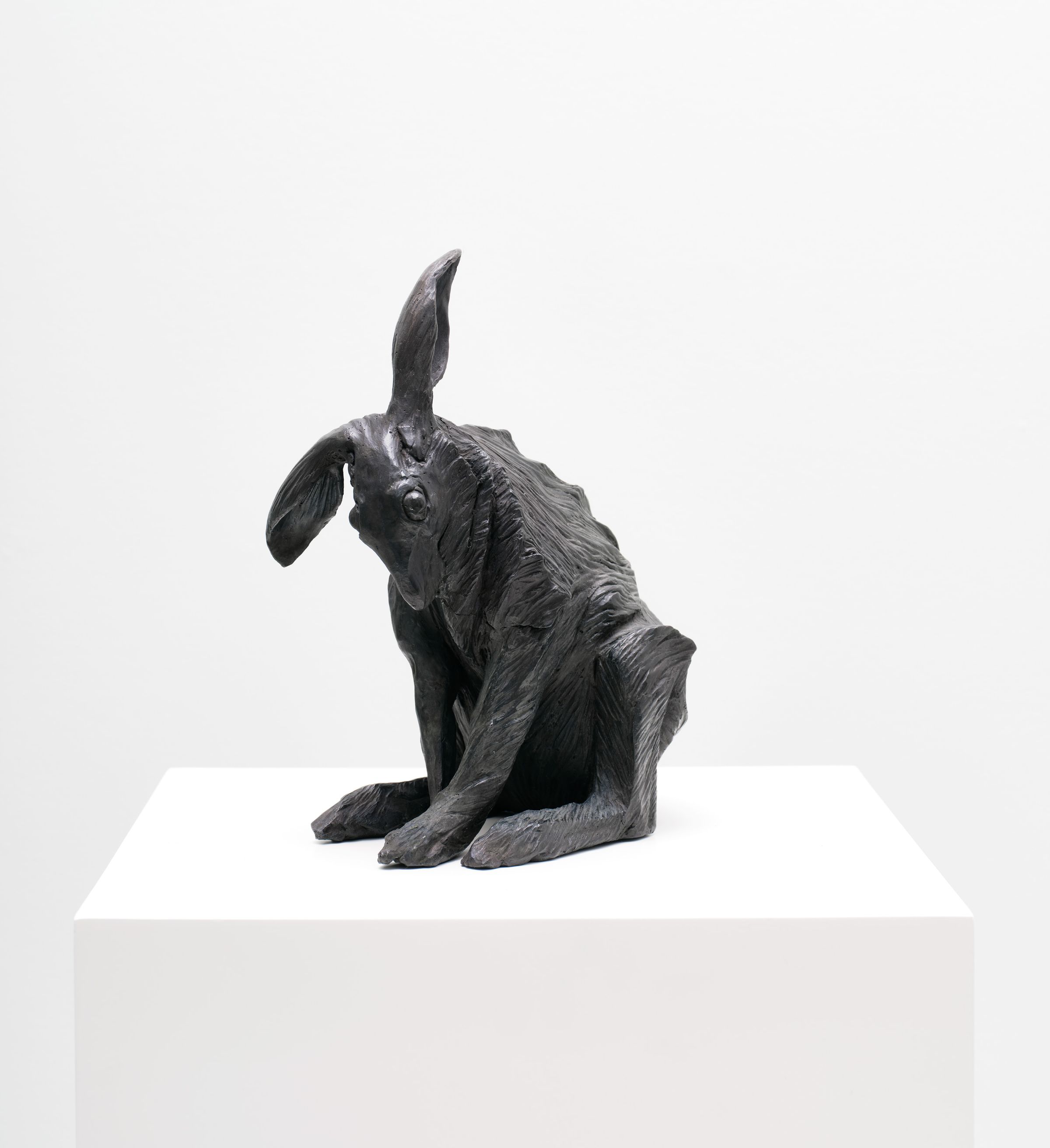 Bronze sculpture of a seated hare with long ears and dark patina.