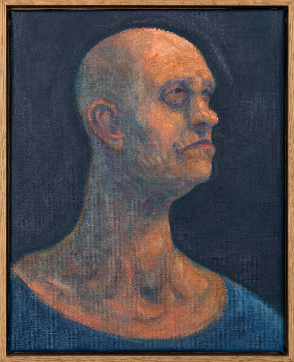 Profile portrait of a bald man with detailed skin tones against a dark background.