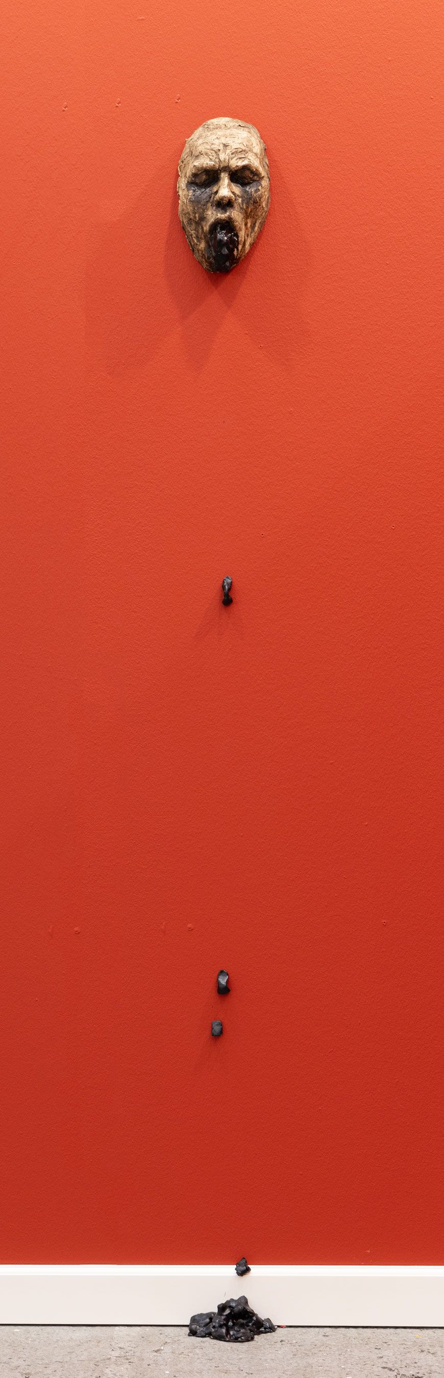 Skulptur af hoved og sort afladning på rød væg, Jacob Rantzau, 2025