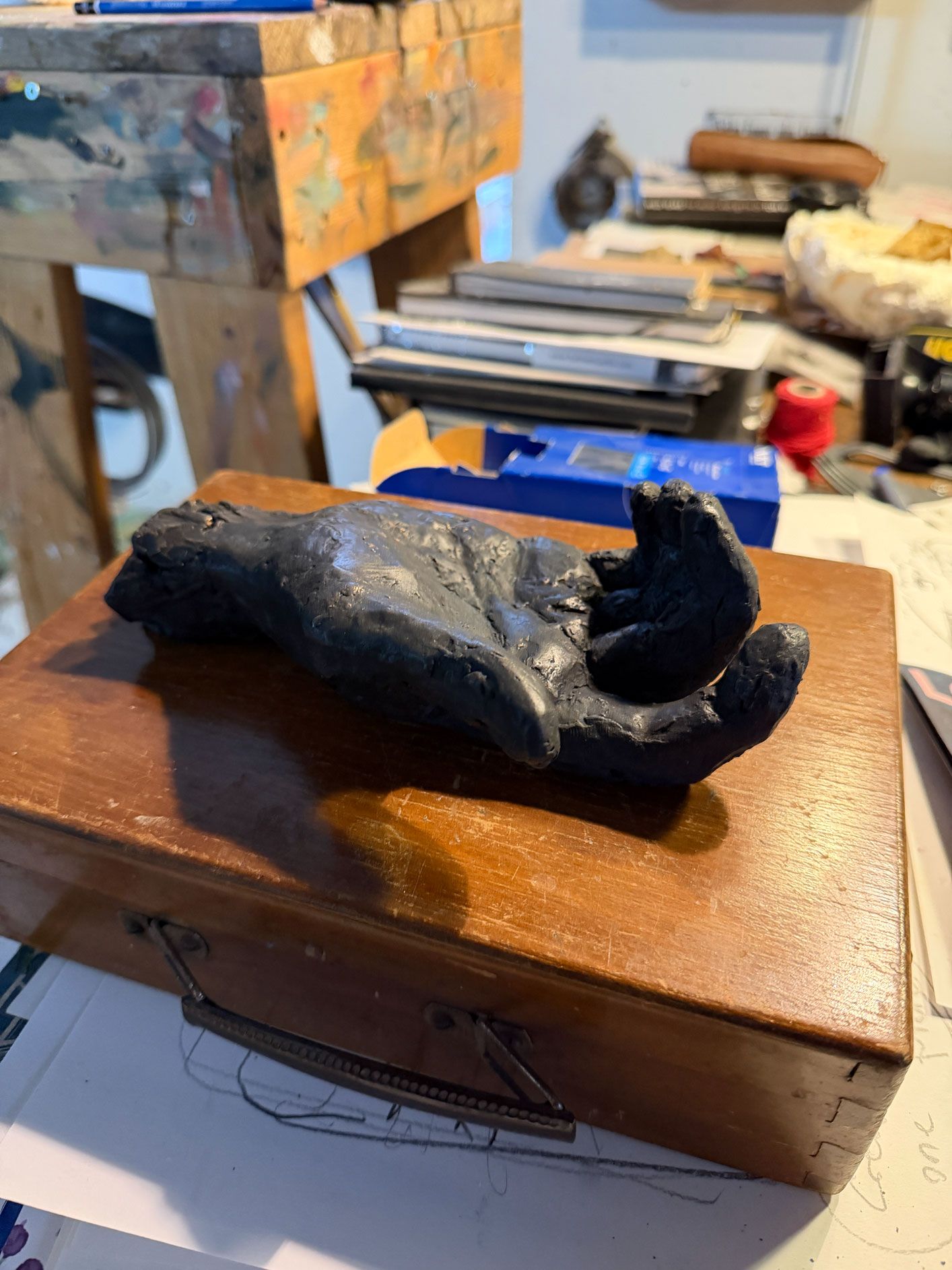 Skulptur af liggende menneskefigur i mørk bronze – ekspressiv form – liggende på trææske – værk af Jacob Rantzau – 2026